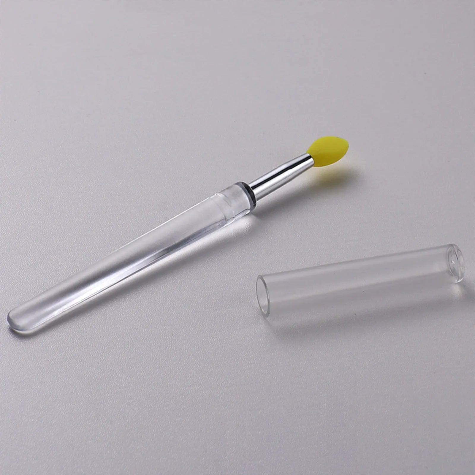 Set of eight colourful reusable silicone lip brushes with hygienic protective caps laid out.