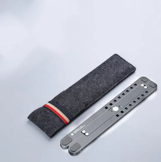 Deep grey portable aluminium laptop stand, folded flat next to an open laptop showing its adjustable height.