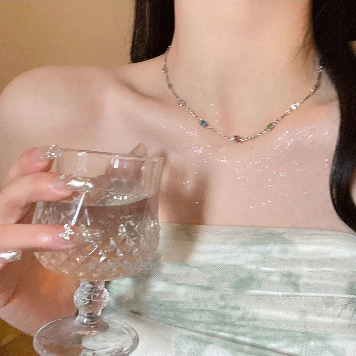 Square geometric clavicle chain necklace in gold tone with artificial crystal details on a model.