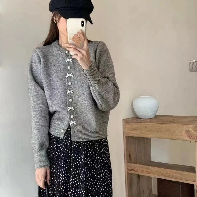 Women's cashmere cardigan sweater with bow and pearl buttons across chest in light blue colour