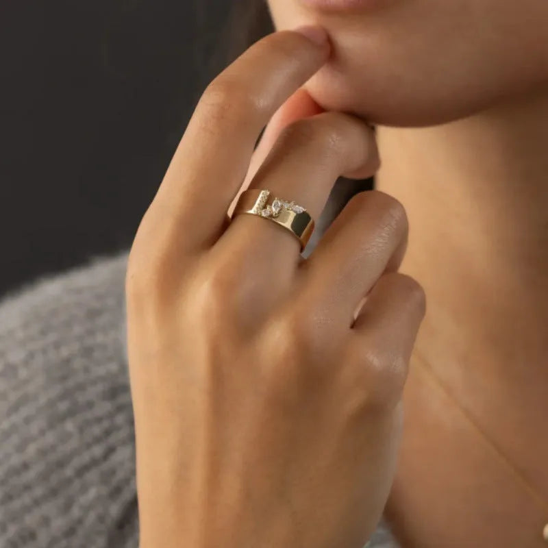 Gold electroplated women's ring with a shining zircon stone, shown on a finger.