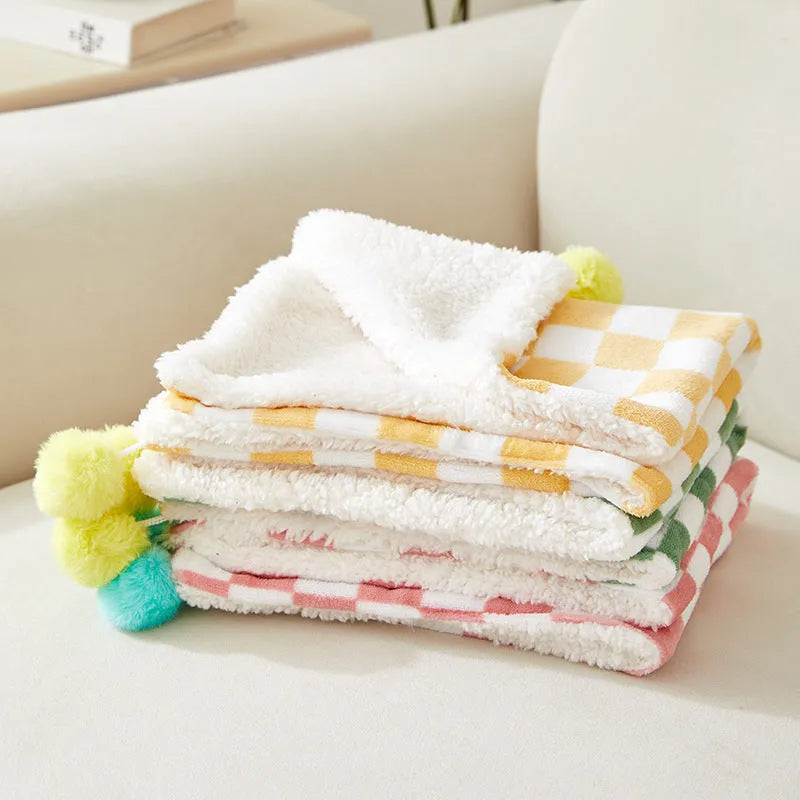 Plush cotton fleece pet blanket with plaid pattern and fur balls in green colour on couch