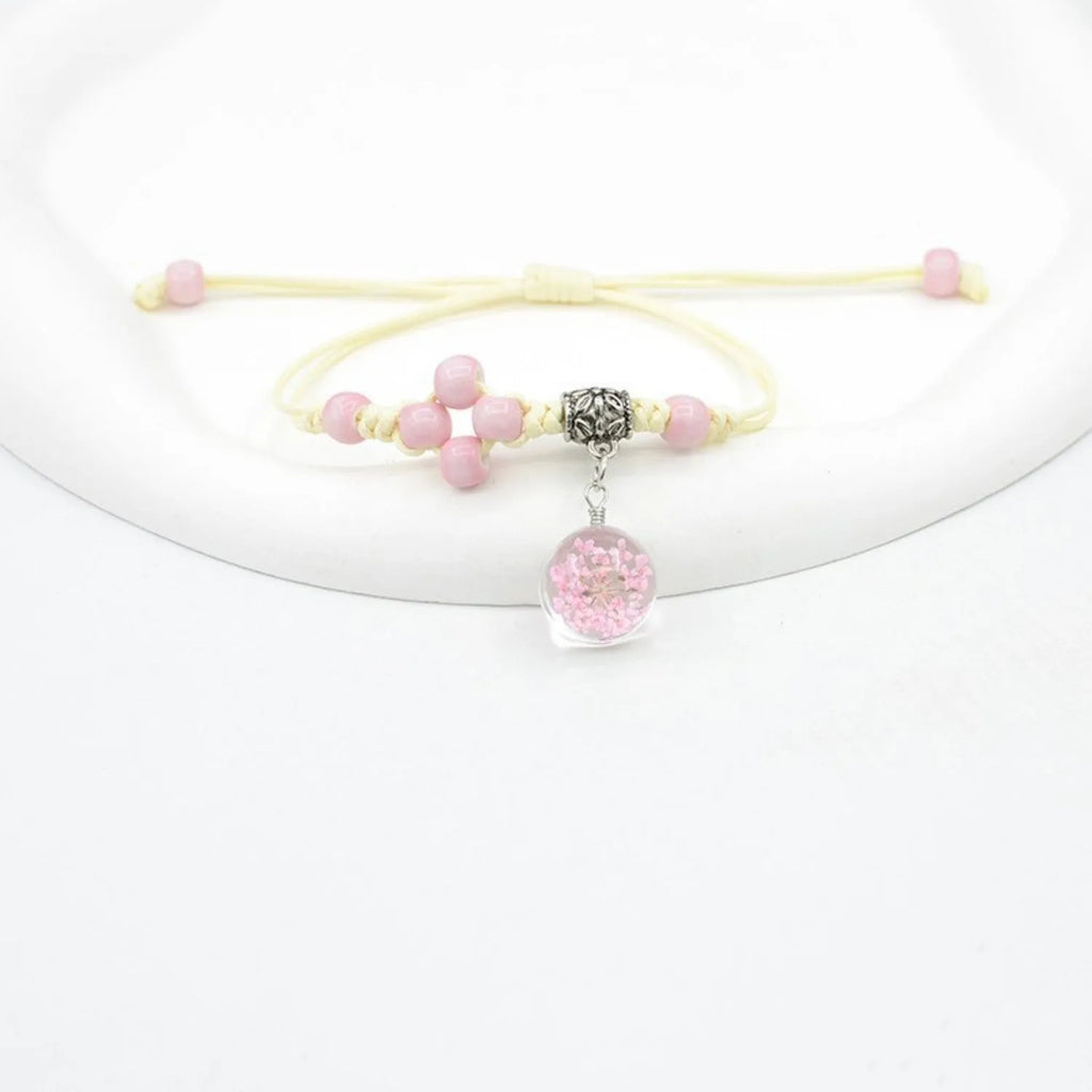 Glass bracelet with large colourful beads containing real dried flowers, on a white background.
