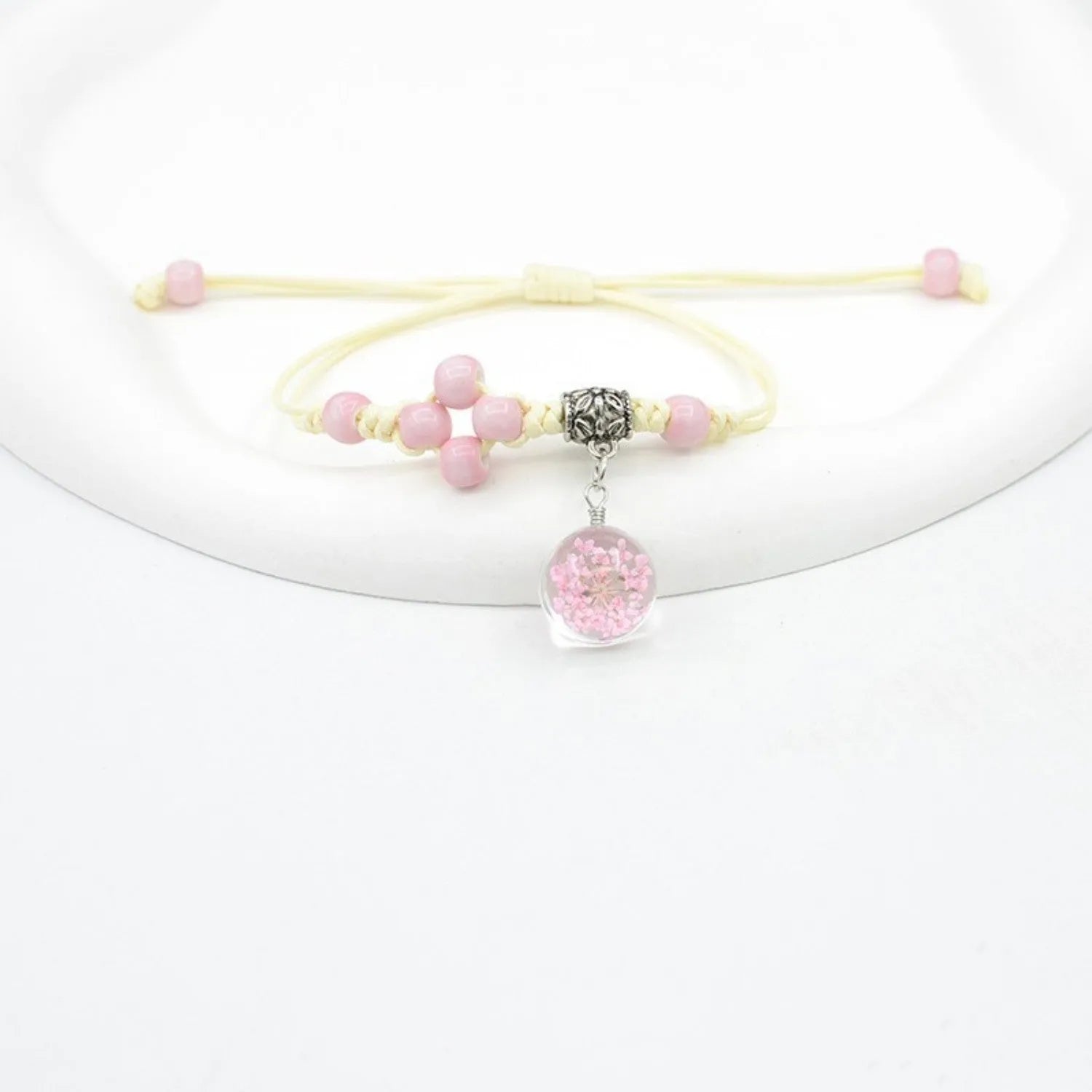 Glass bracelet with large colourful beads containing real dried flowers, on a white background.