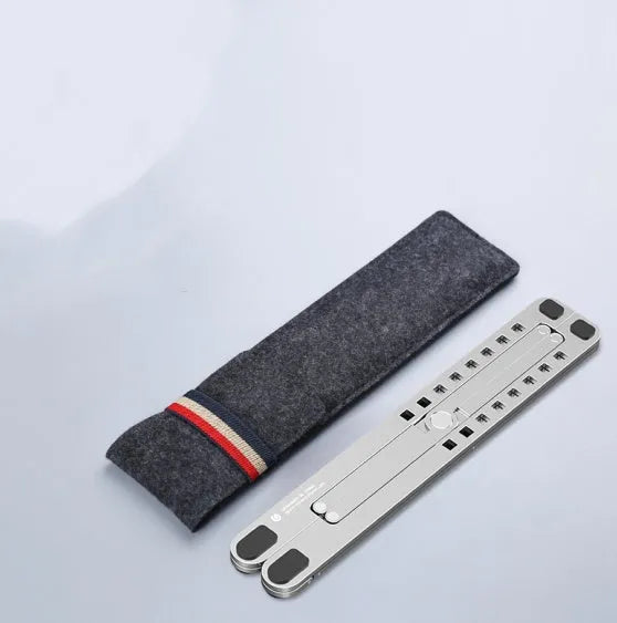 Deep grey portable aluminium laptop stand, folded flat next to an open laptop showing its adjustable height.
