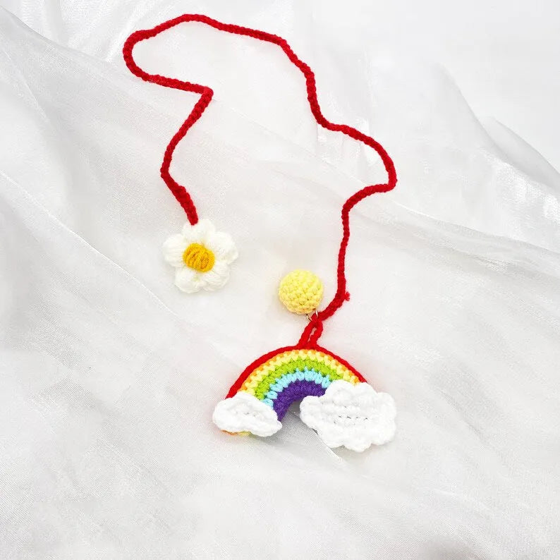 Handmade crocheted avocado-shaped rainbow flower car pendant hanging, shown in multiple colour options.