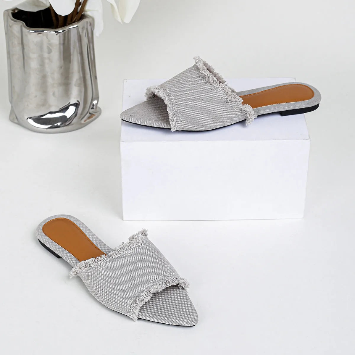 Women's casual denim flat slippers with leather lining and tassel detail.