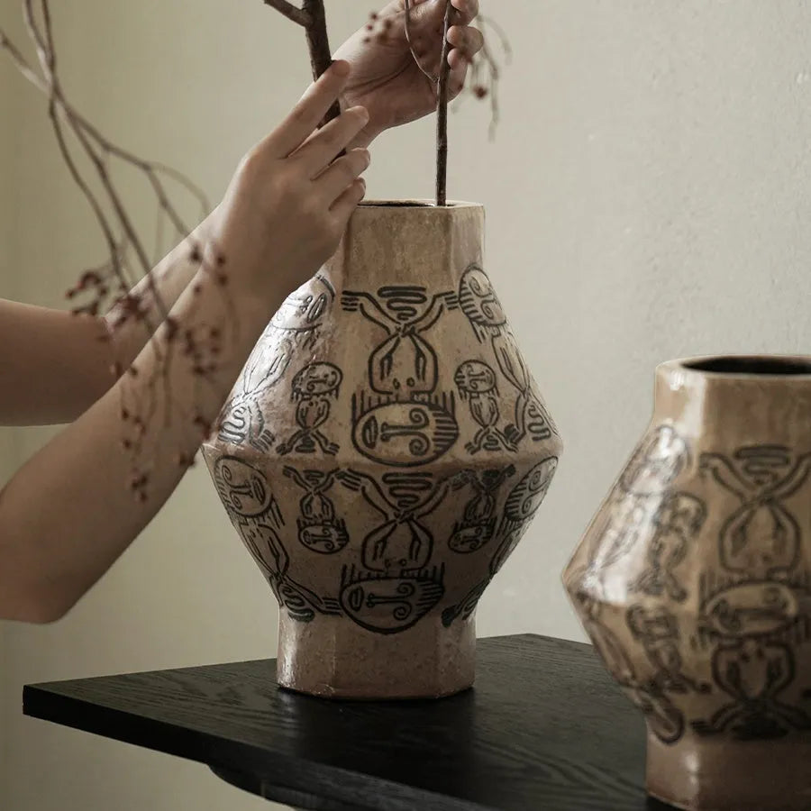Hand-painted ceramic vase with carved tribal totem art in cylindrical shape.
