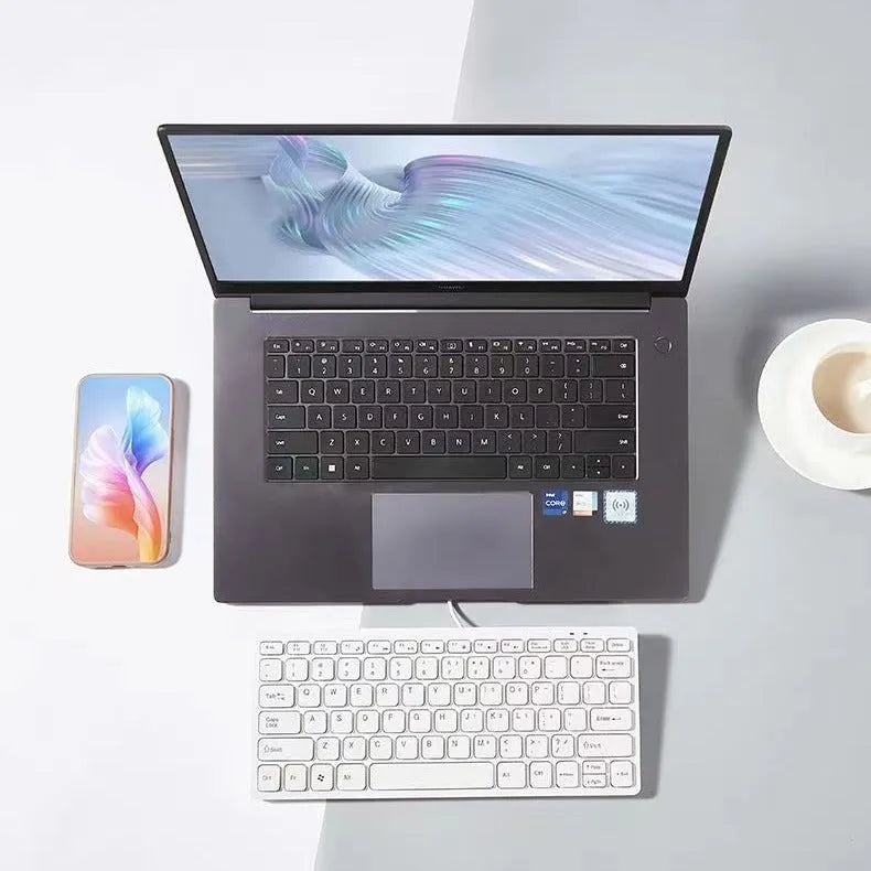 Compact USB wired keyboard in black, white, pink, or blue colour options on a desk.