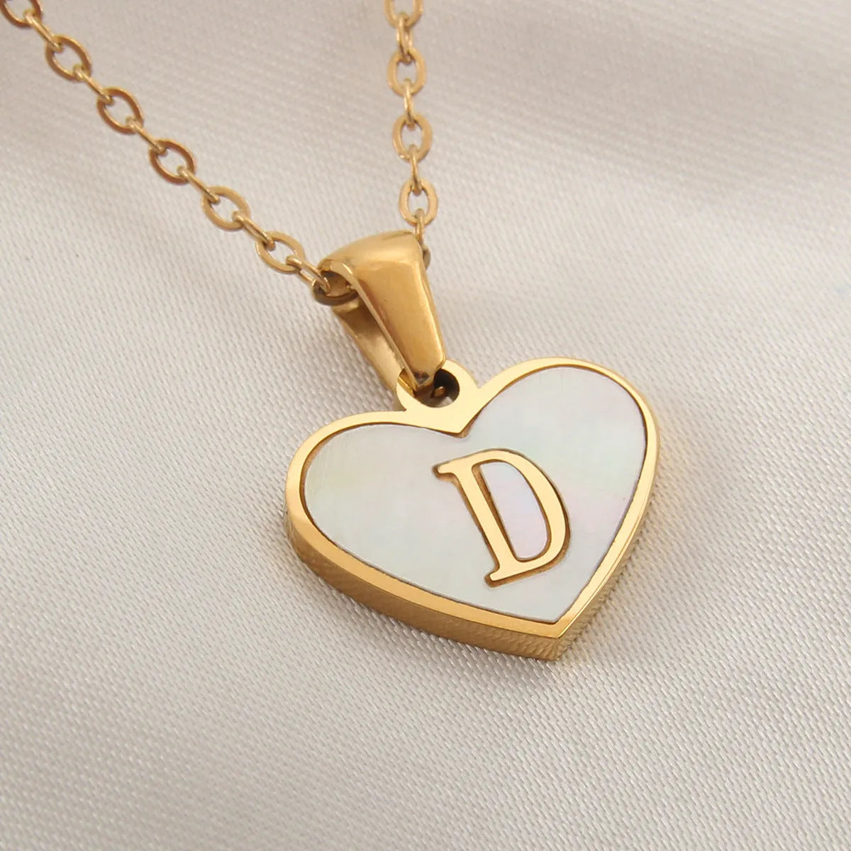 Gold heart necklace with white shell detail and personalised initial letter on adjustable chain