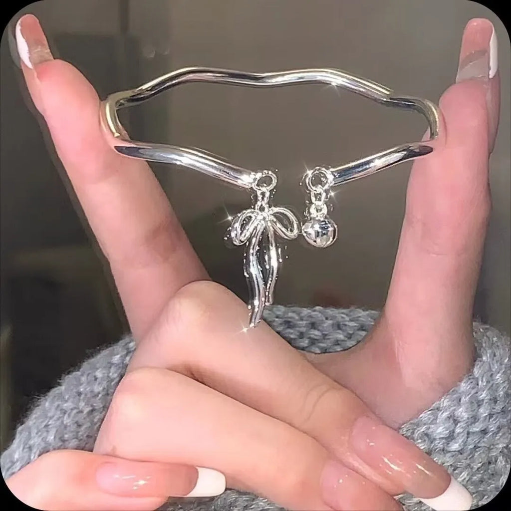Silver adjustable bracelet with a large bow-shaped clasp on a white background.