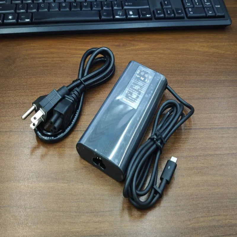 Black 65W USB-C laptop power adapter with six international travel plug cords.