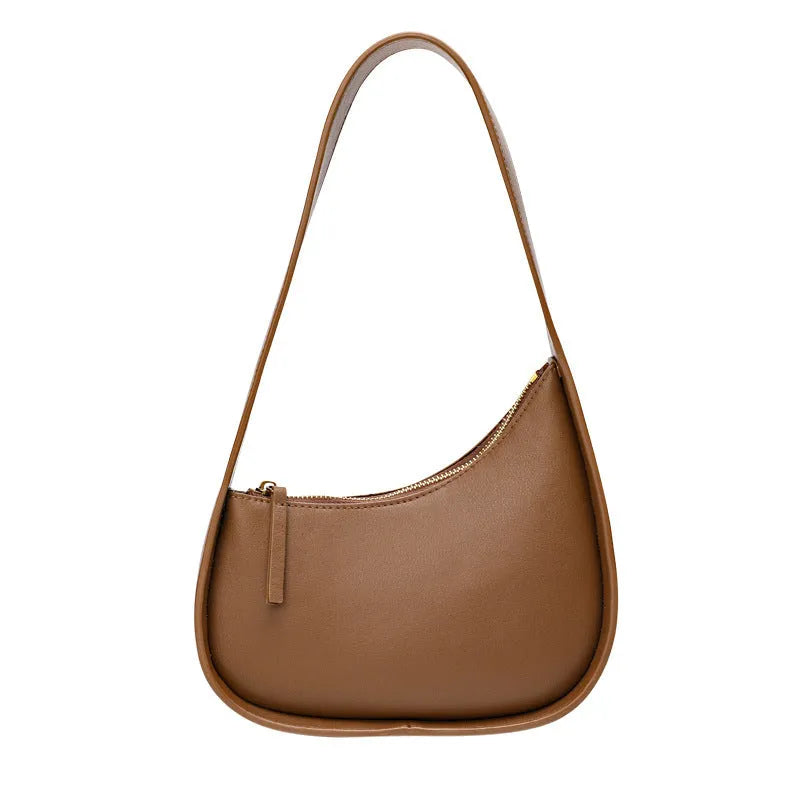 Women's half moon shaped leather shoulder bag in light brown with an adjustable wide strap.