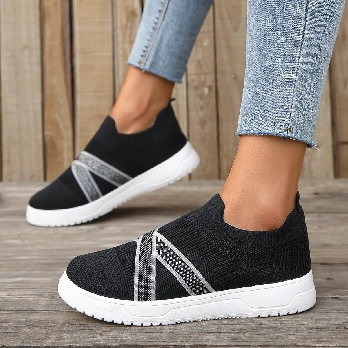Black women's flyknit mesh casual shoes with a flat rubber sole and a tassel detail on the upper.