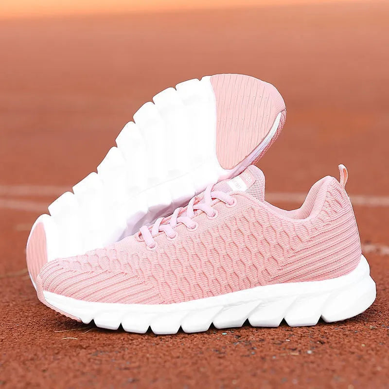 Women's running shoes in black, pink, or white with a woven fly knit upper and textured outsole.