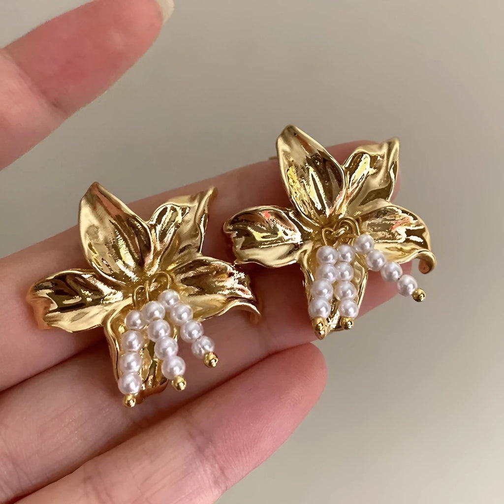 Gold H1795 metal flower earrings with a pearl centre, showing exaggerated floral shape and niche style.