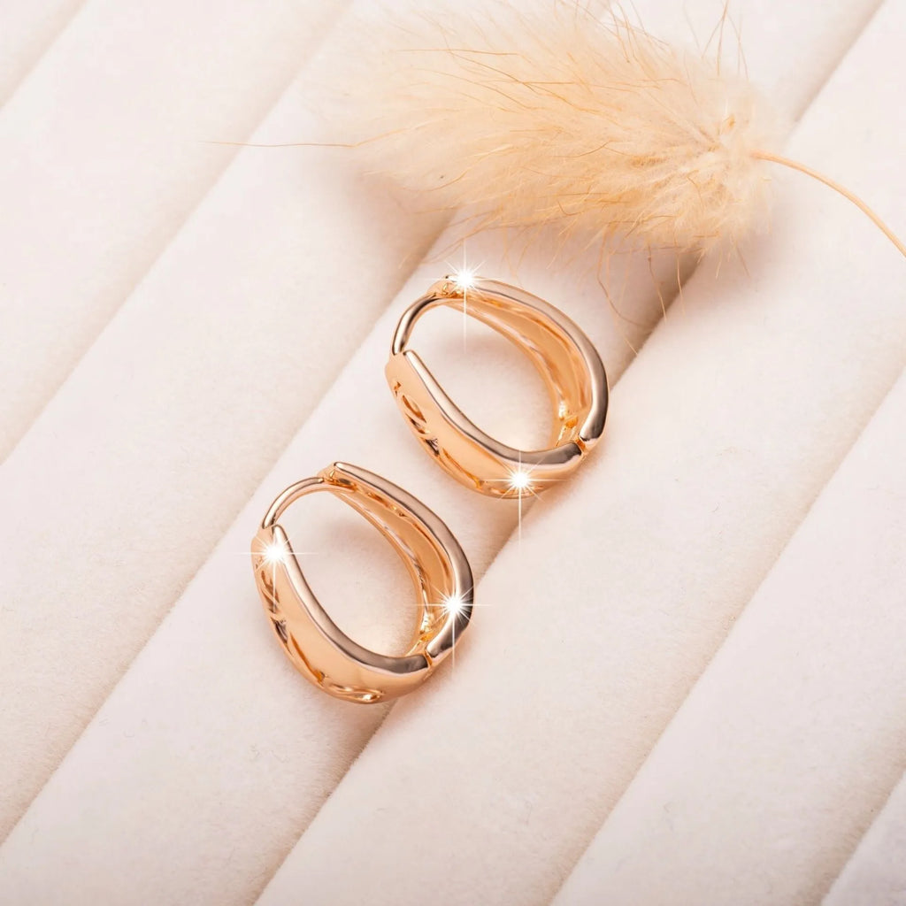 Rose gold hollow carved U-shaped copper earrings on light background