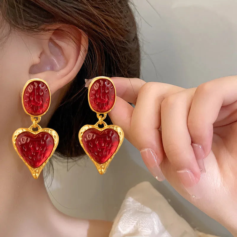A pair of oval-shaped, pleated love heart stud earrings in alloy, shown in various colours.