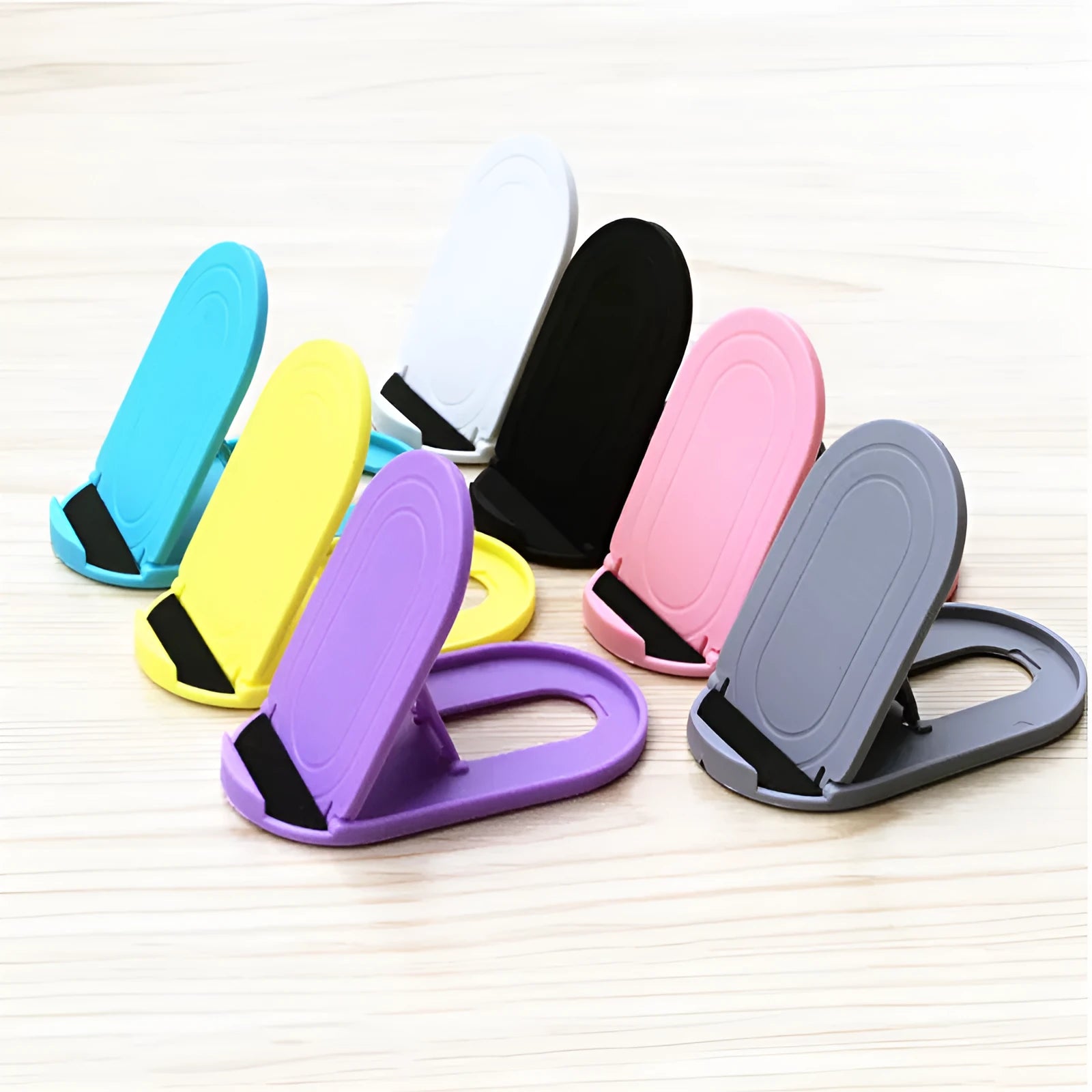 Plastic mobile phone stand with adjustable lazy bracket in six colour options on tabletop