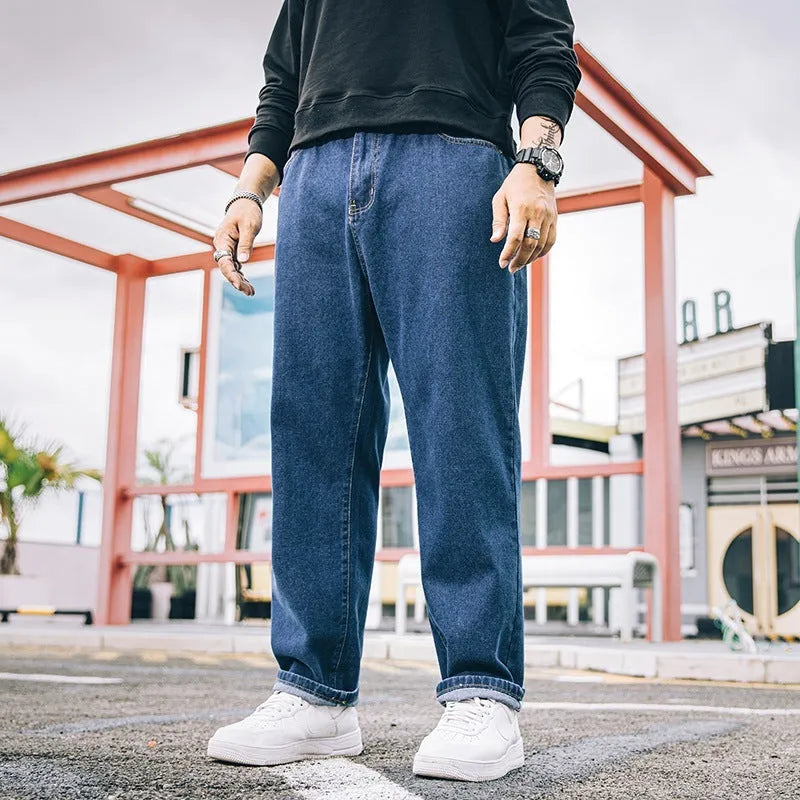 Man wearing dark blue loose straight-cut cotton jeans with a mid-waist and zipper fly.