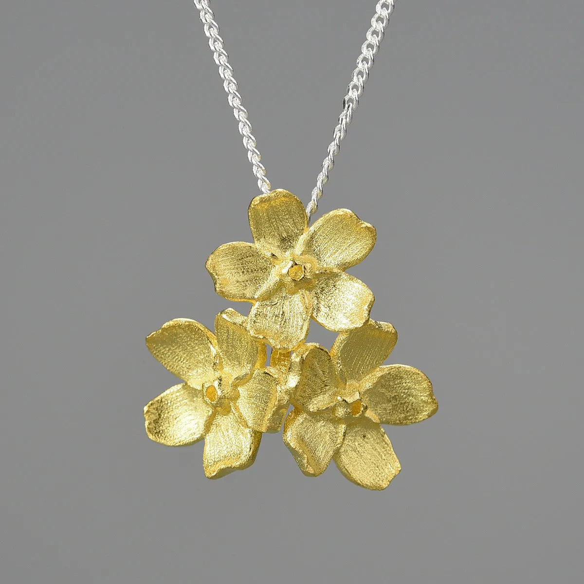 Silver open mouth Myosotis Sylvatica flower pendant with electroplated finish on a dark background.
