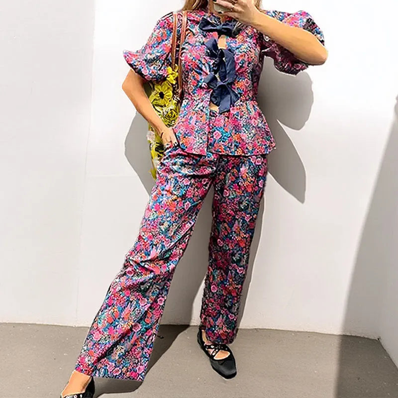 Women's floral print trouser suit set featuring a puff sleeve top with tie-neck and matching trousers.