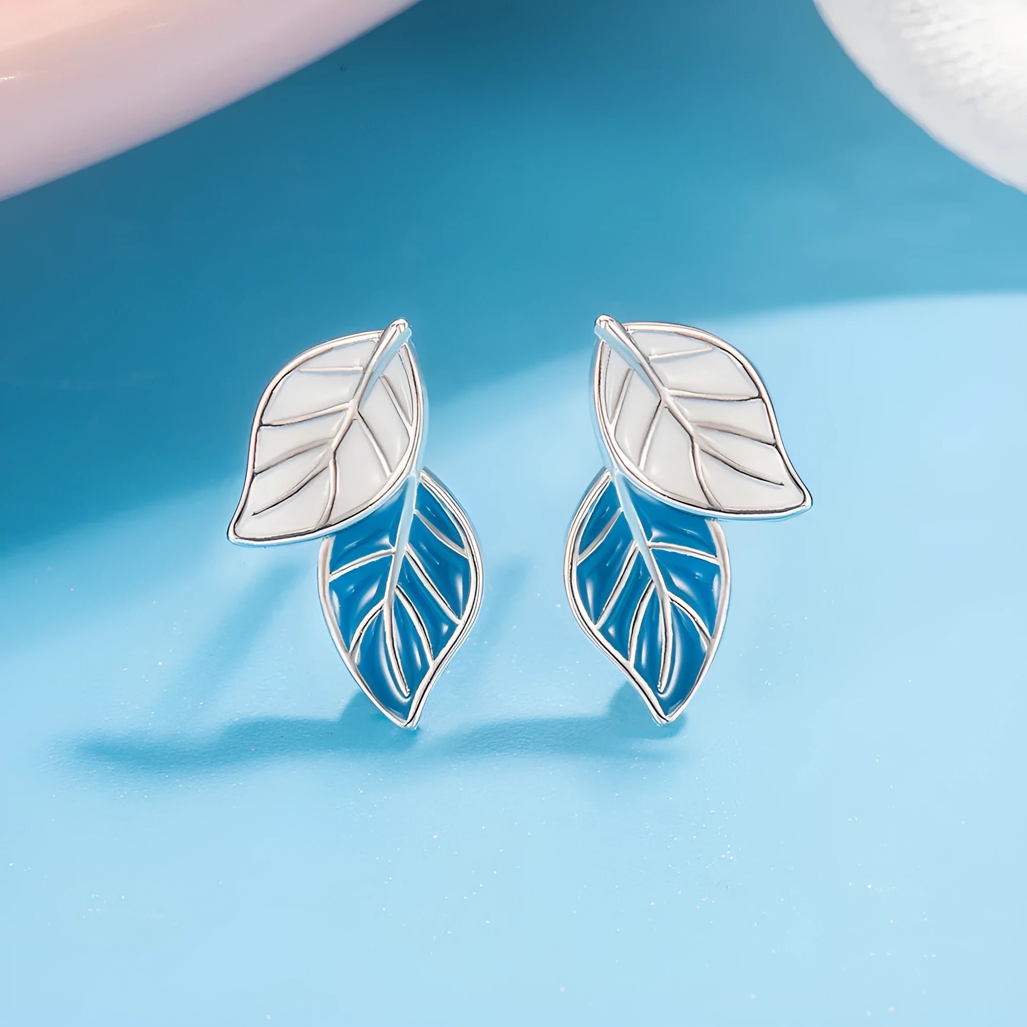 White gold plated copper leaf-shaped stud earrings for women on white background