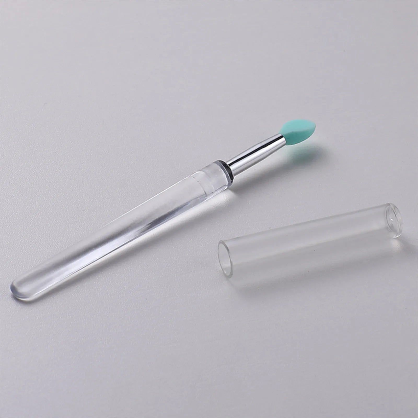 Set of eight colourful reusable silicone lip brushes with hygienic protective caps laid out.