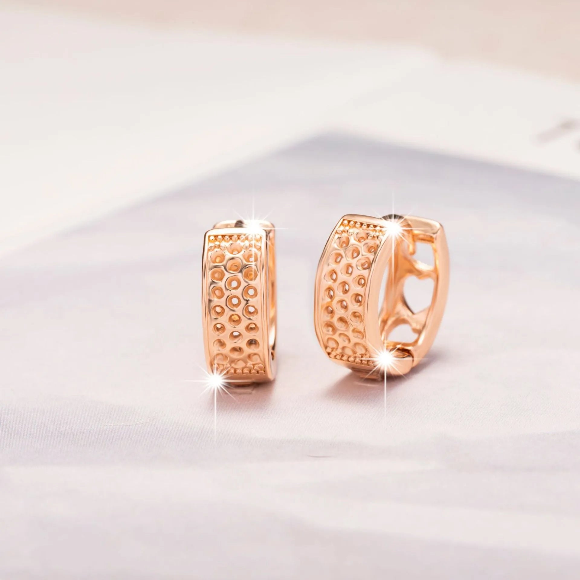 Circular rose gold earrings with three cut-out heart shapes