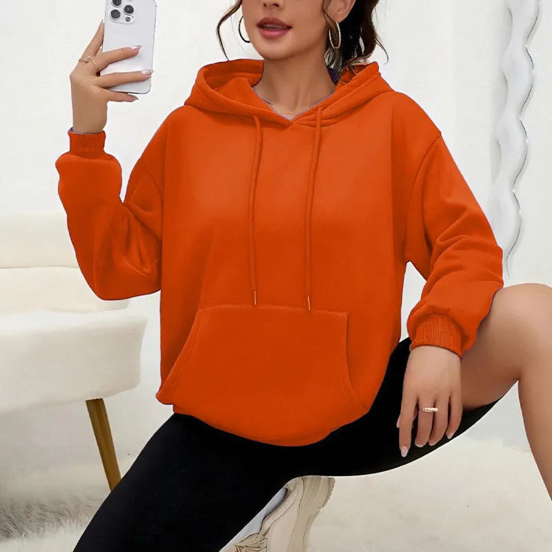 Woman wearing a loose grey drawstring waist sweatshirt with front pockets and long sleeves.
