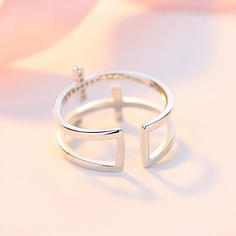 Adjustable double cross geometric ring made of copper with white gold finish and inlaid zircon stones.