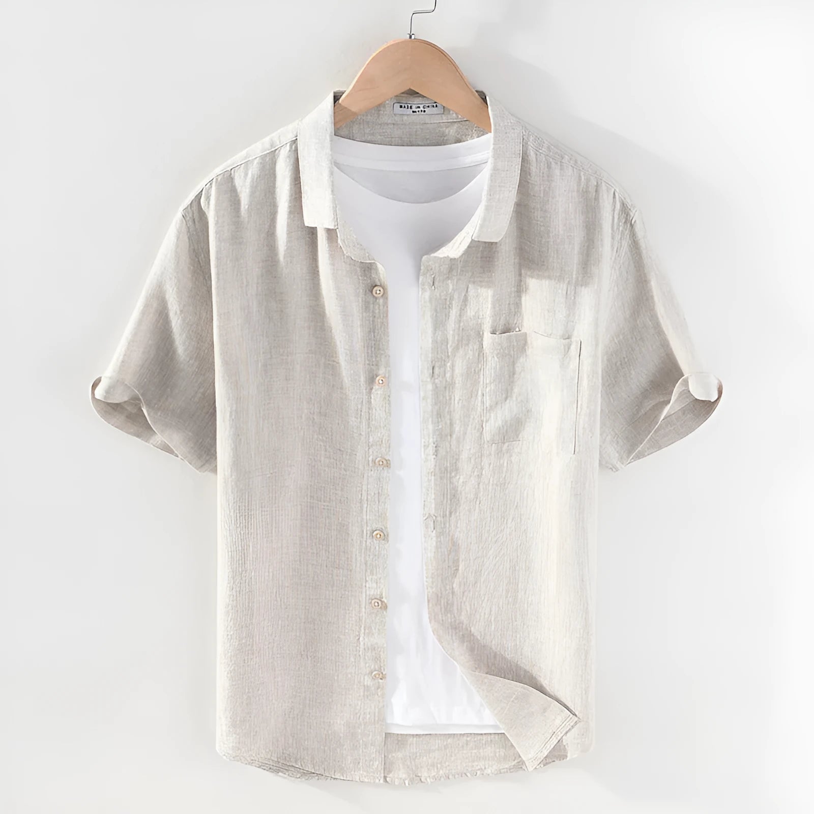 Men's raw jute coloured linen short sleeve shirt with a square collar laid flat.