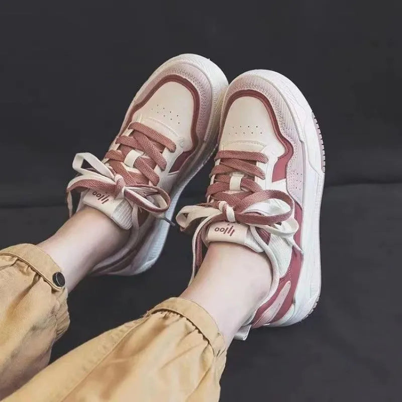 Pink and beige low-top sneakers with a rubber sole and imitation leather upper.