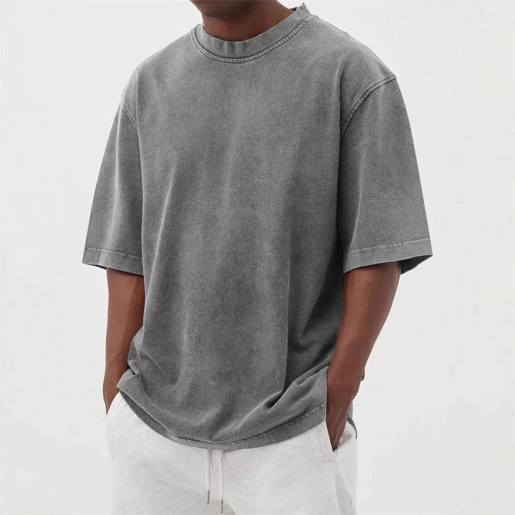 Man wearing a loose-fit, stone-washed distressed pullover T-shirt in a solid colour.