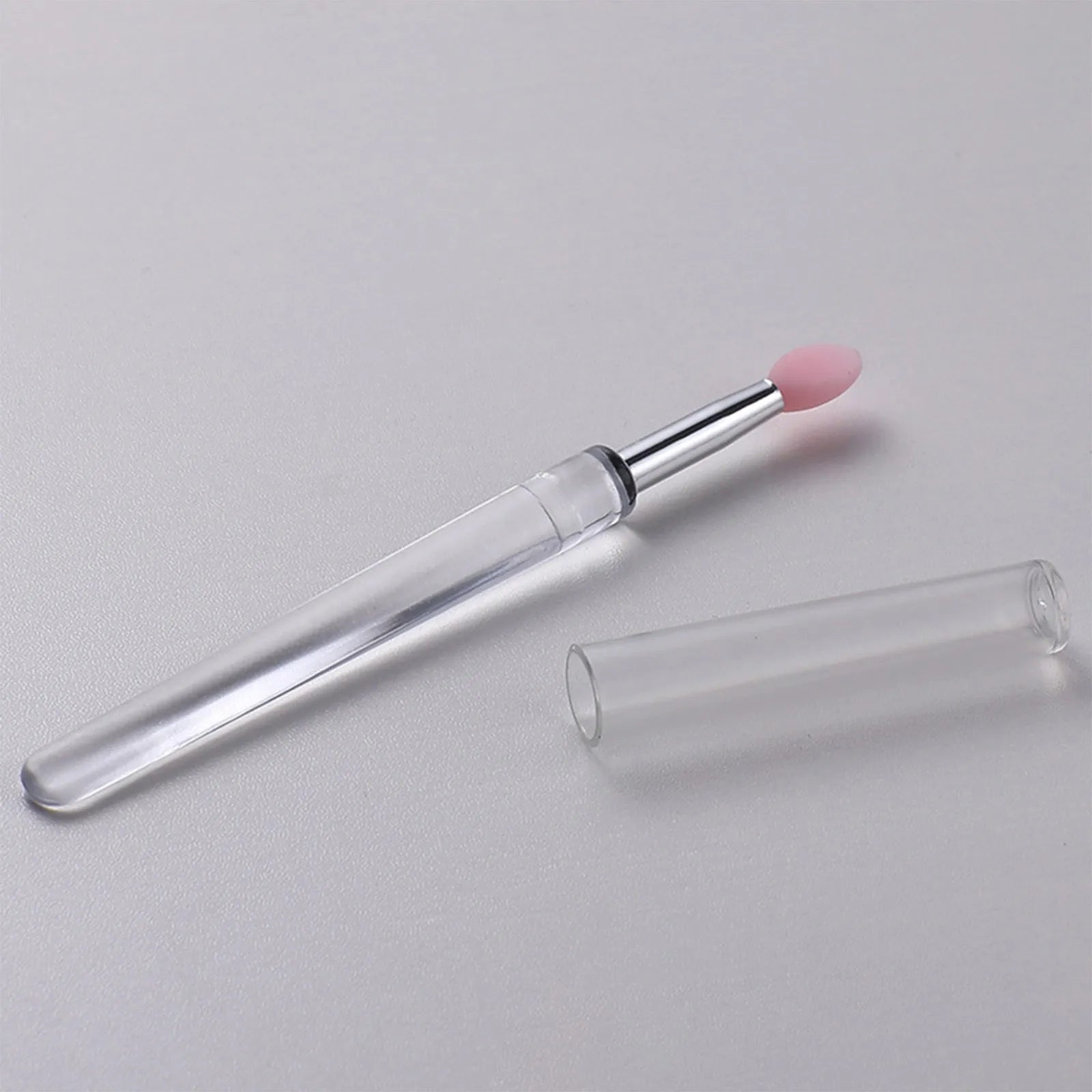 Set of eight colourful reusable silicone lip brushes with hygienic protective caps laid out.