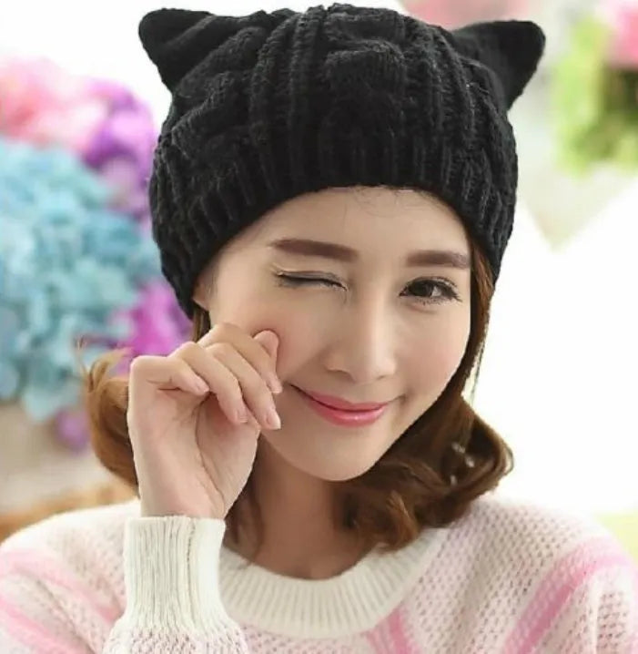 Handmade red knitted beanie with 3D cat ears on a white background