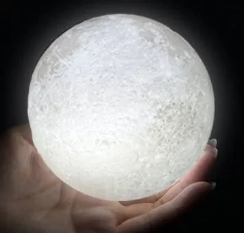 3D printed spherical moon lamp with textured surface on a wooden stand, showing white LED light.