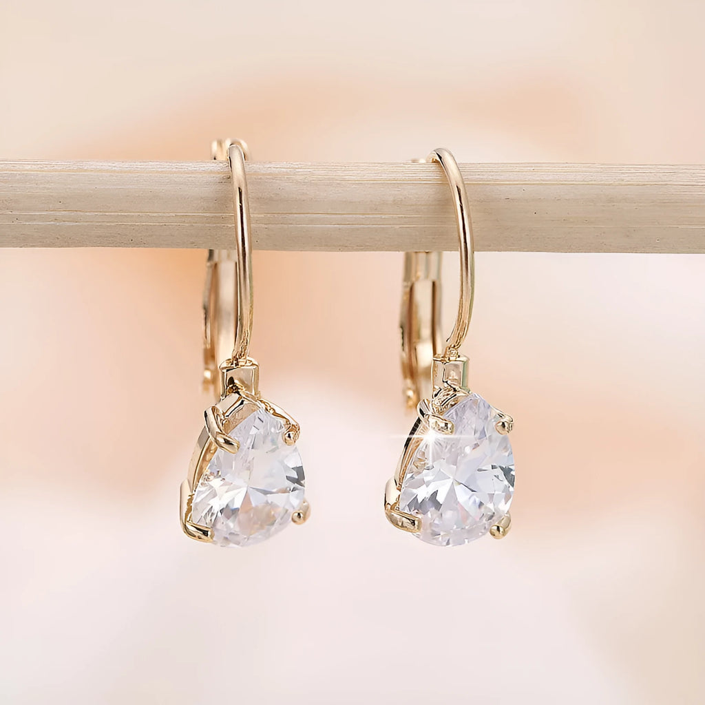 Drop-shaped metal earrings in gold or platinum finish with inlaid gem detailing
