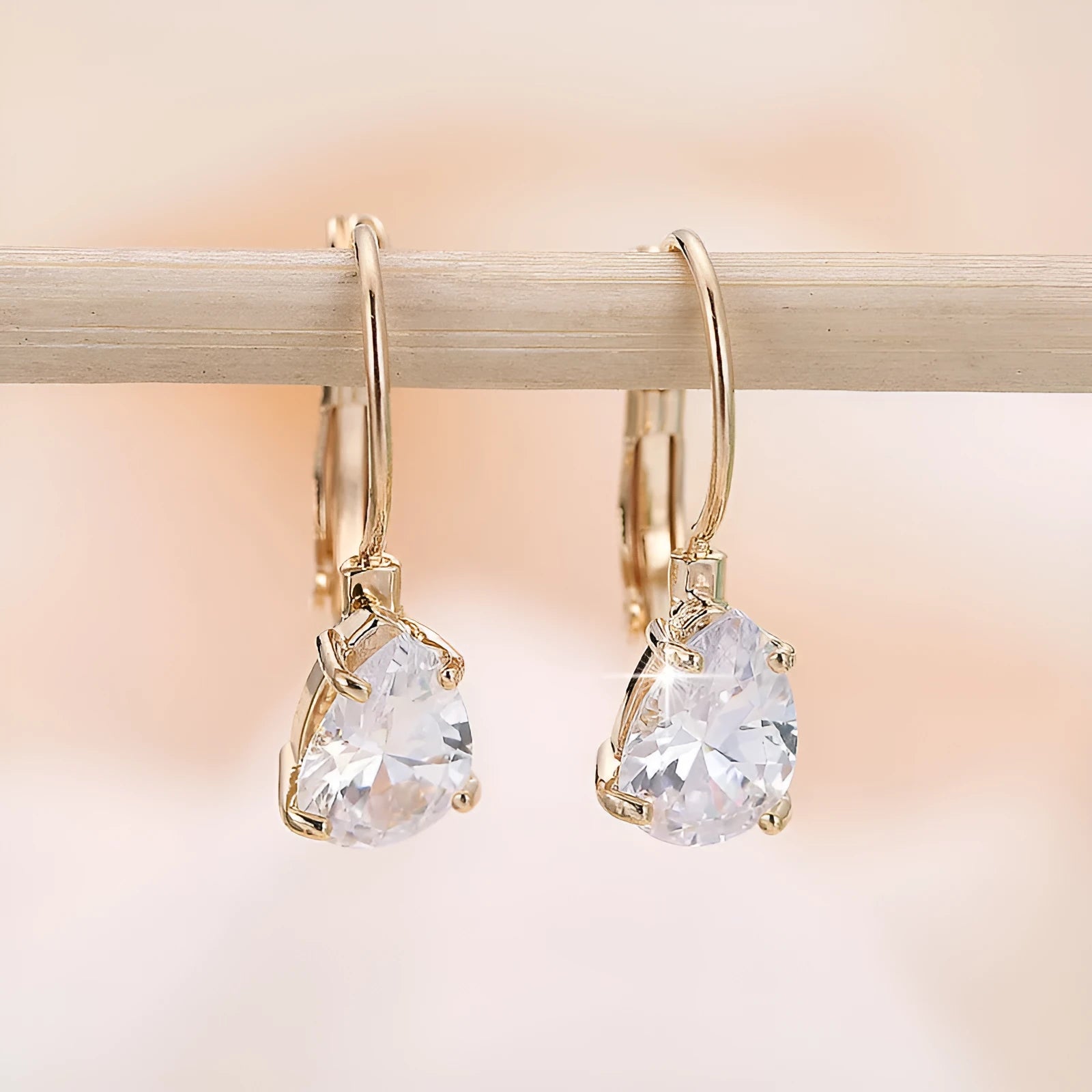 Drop-shaped metal earrings in gold or platinum finish with inlaid gem detailing
