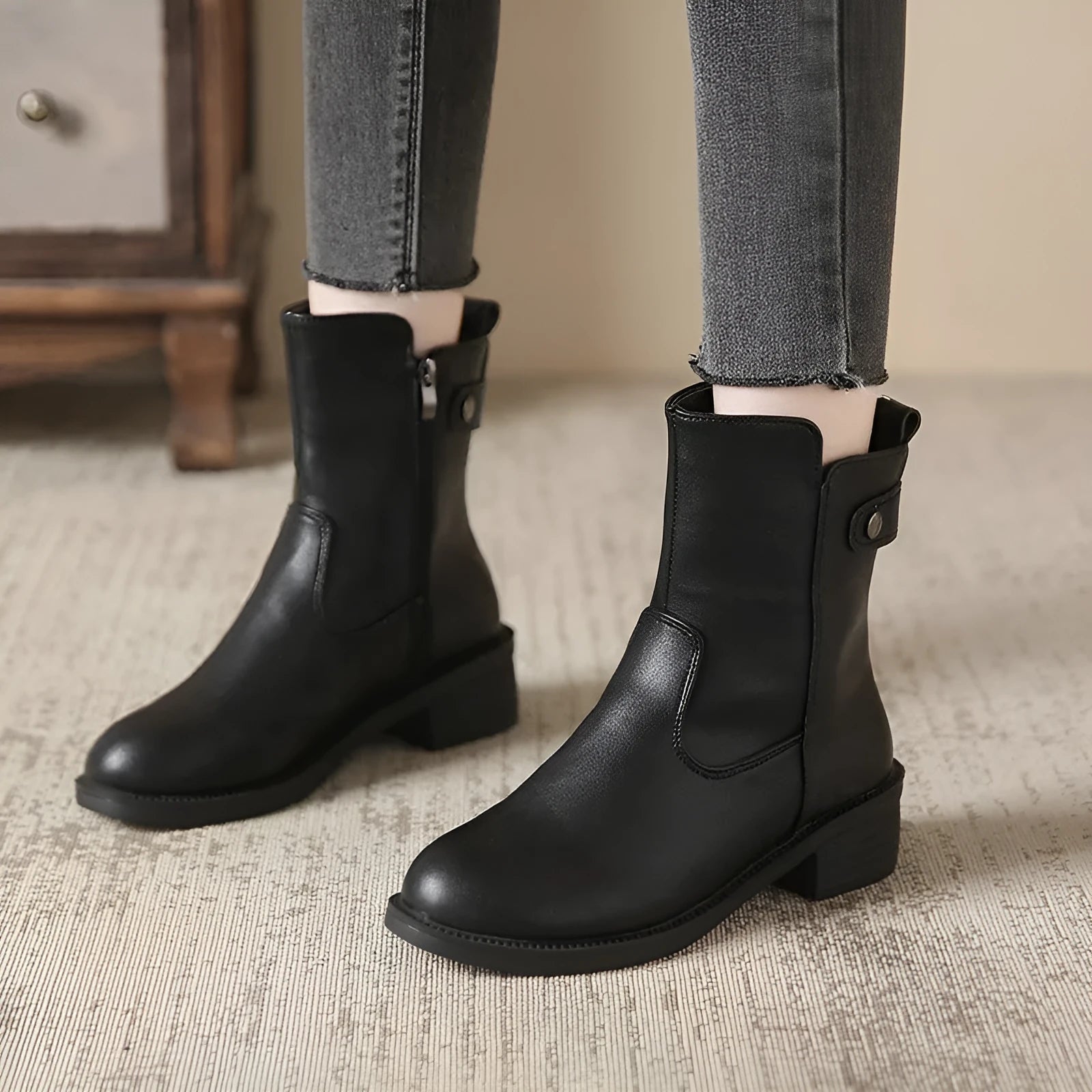 Black women's short ankle boots with a side zip, low heel, and round toe on a rubber sole.