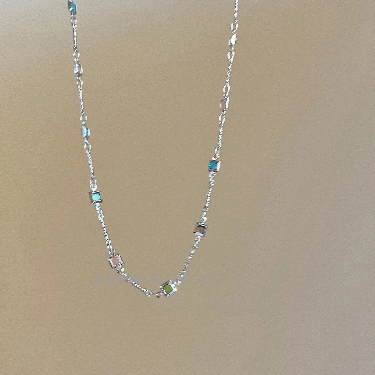 Square geometric clavicle chain necklace in gold tone with artificial crystal details on a model.