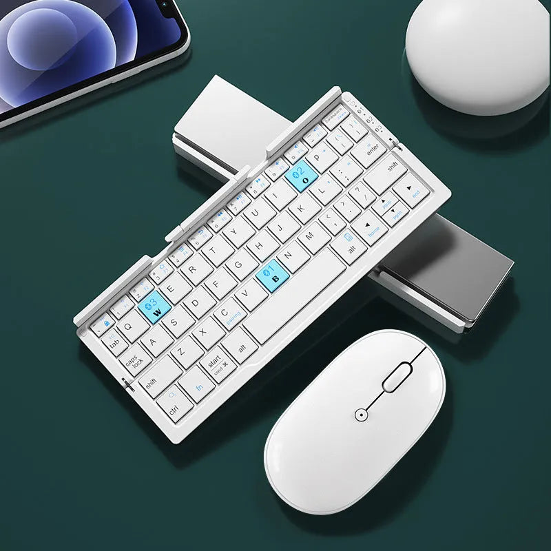 Silver white folding Bluetooth keyboard open next to a smartphone on its built-in metal stand.