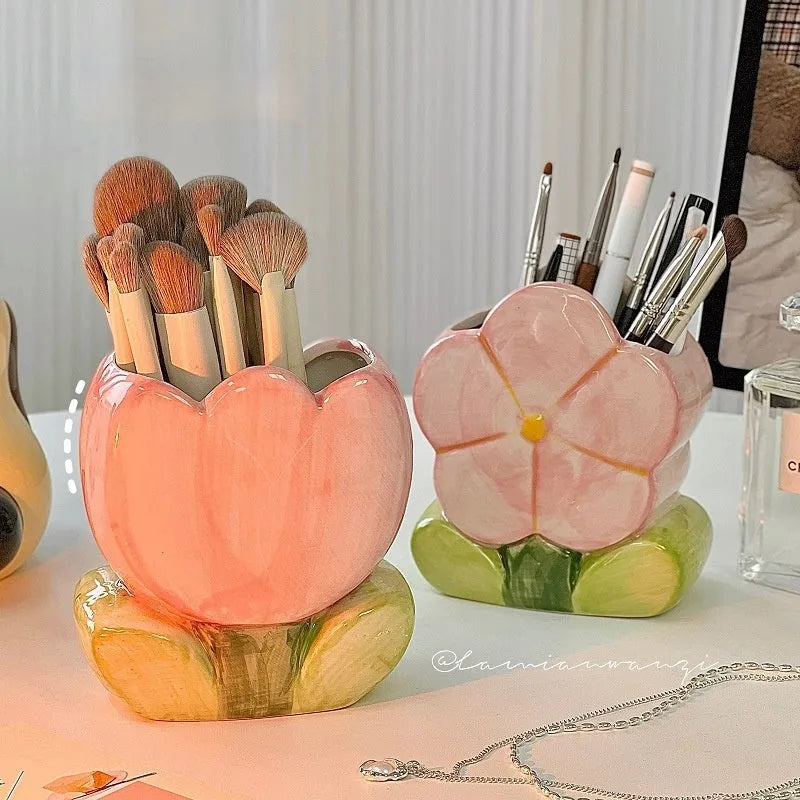 Ceramic pen holder box with floral pattern and lid on a wooden desk.