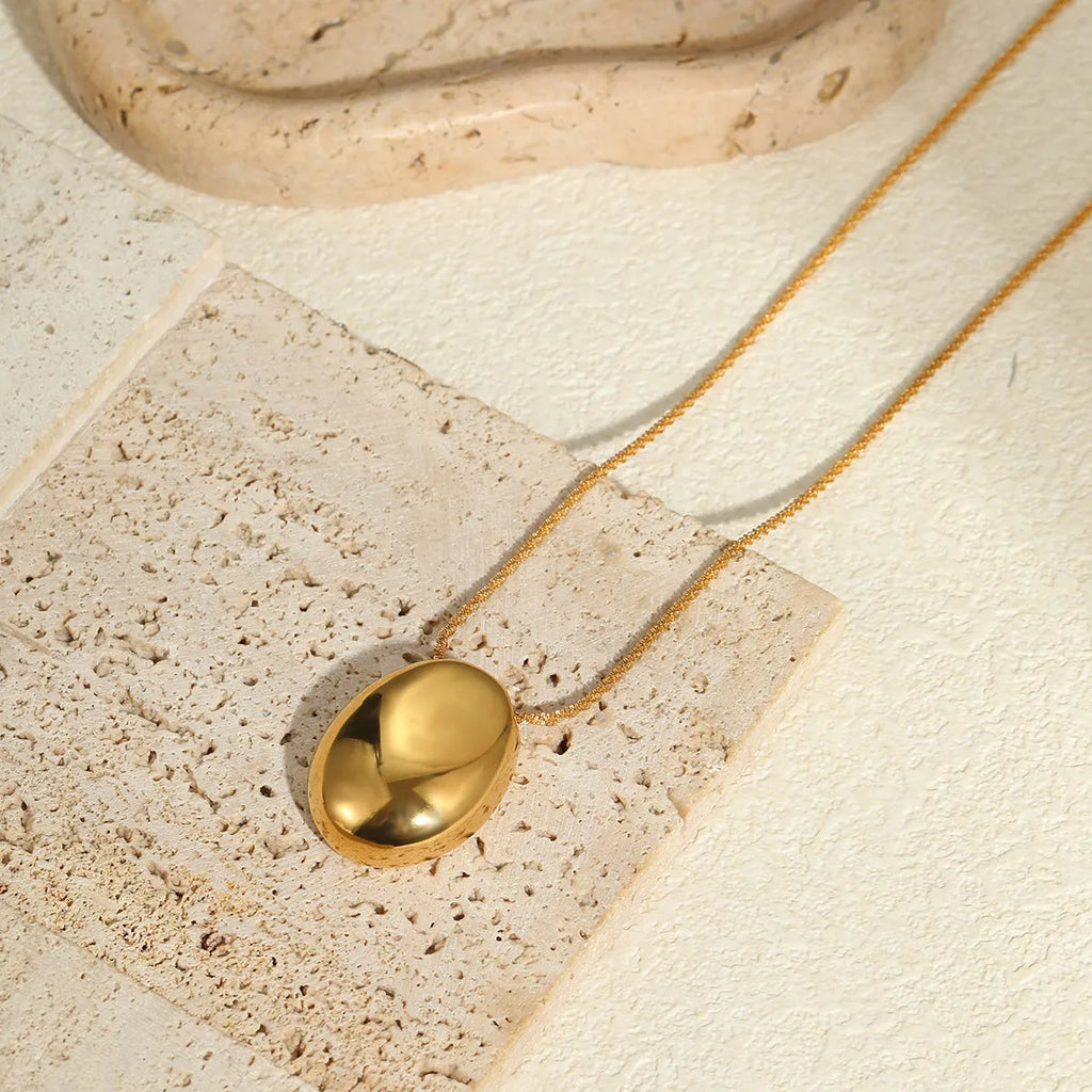 Gold-plated geometric pendant necklace with stainless steel chain on black background