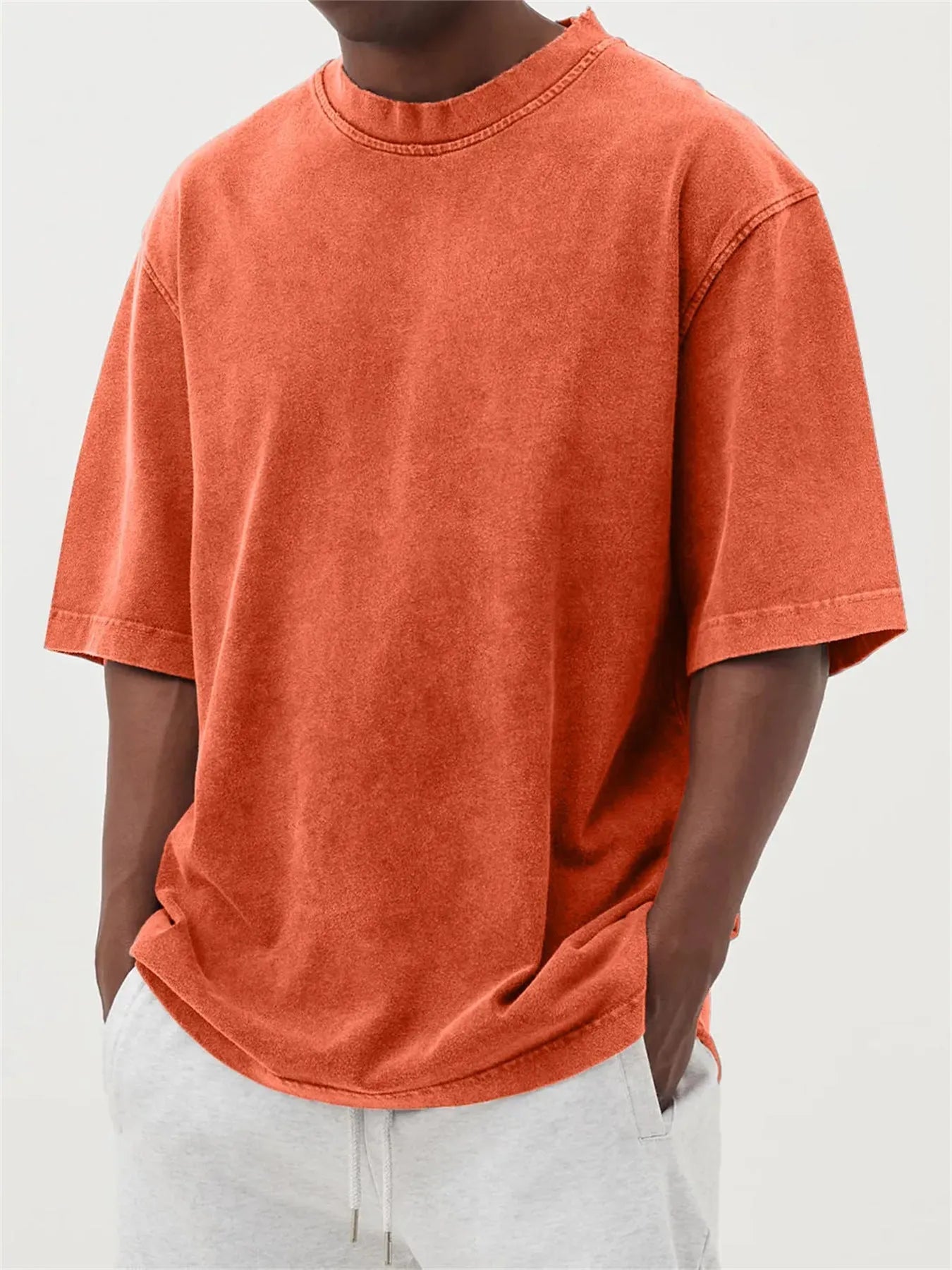 Man wearing a loose-fit, stone-washed distressed pullover T-shirt in a solid colour.