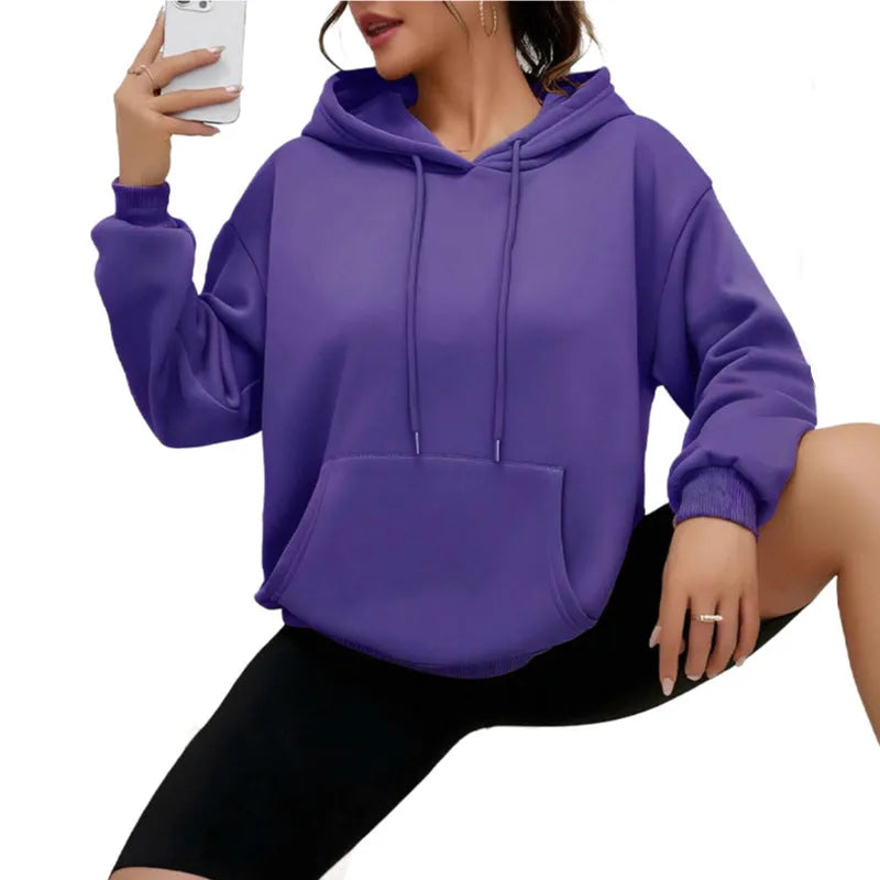 Woman wearing a loose grey drawstring waist sweatshirt with front pockets and long sleeves.
