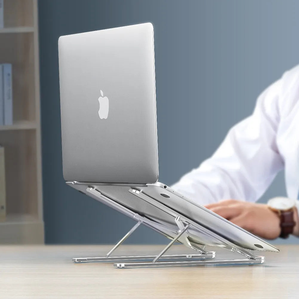Deep grey portable aluminium laptop stand, folded flat next to an open laptop showing its adjustable height.