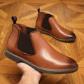 Men's black formal pointed-toe leather boots with a square heel and rubber sole on a plain background.