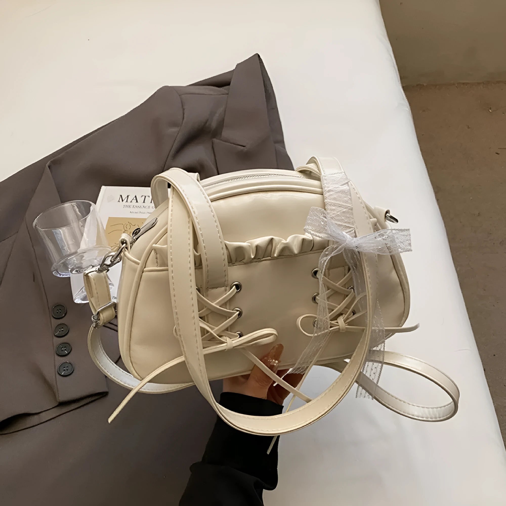 Milky white women's PU leather shoulder bag with a removable bandage bow and visible sewing thread detailing