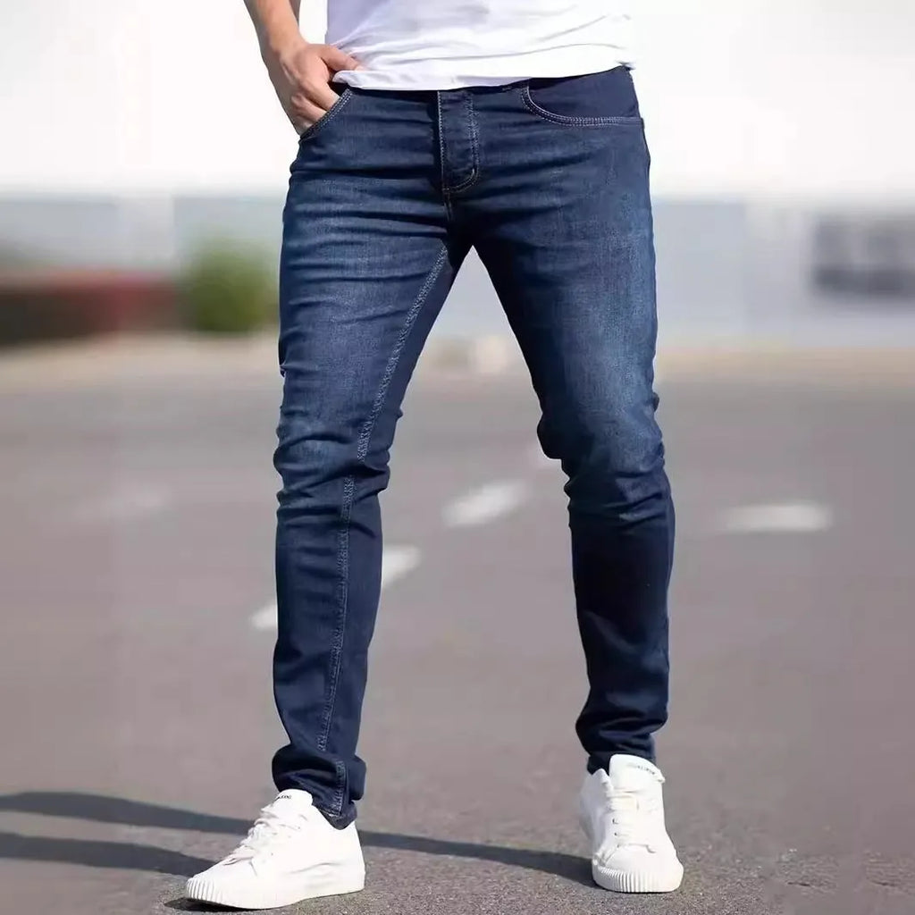 Men's dark blue slim fit skinny jeans with a mid waist and zipper fly, laid flat.